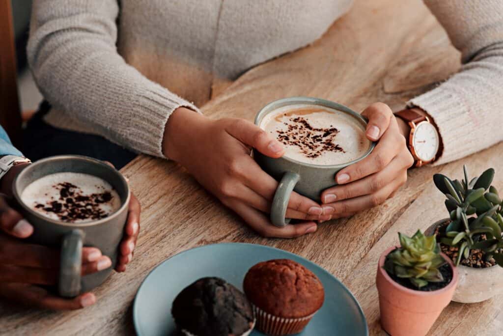 Two people exploring Brooklyn's best coffee shops while holding cups of coffee and cupcakes.