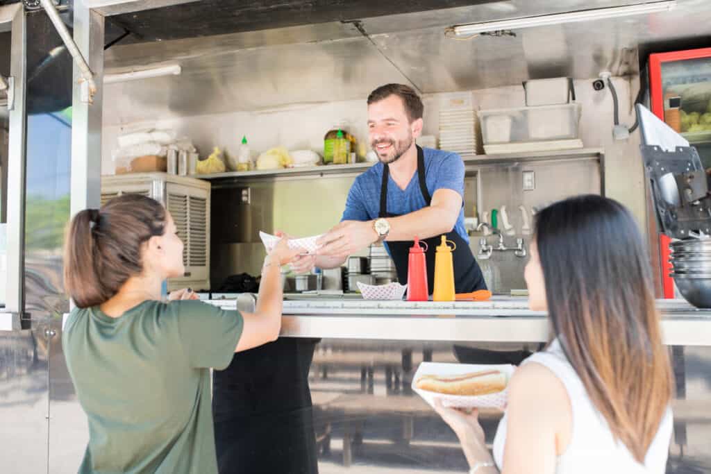 Girls buying hot dogs from food truck