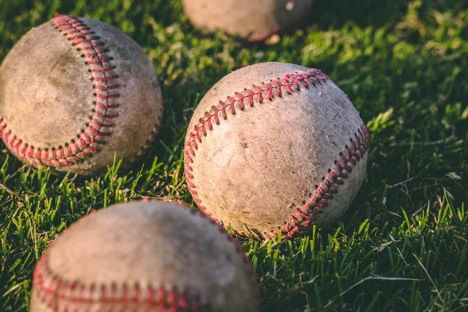 A group of baseballs sitting on the grass.