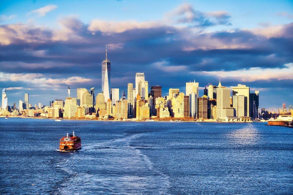 A boat sails across the water in front of a city skyline.