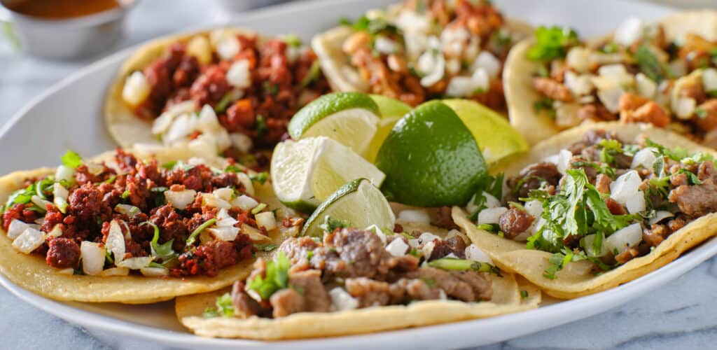 platter of mexican street tacos with carne asada, chorizo, and al pastor in corn tortillas