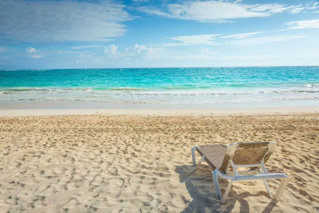 A beach chair on the sand next to the ocean in Cancun.