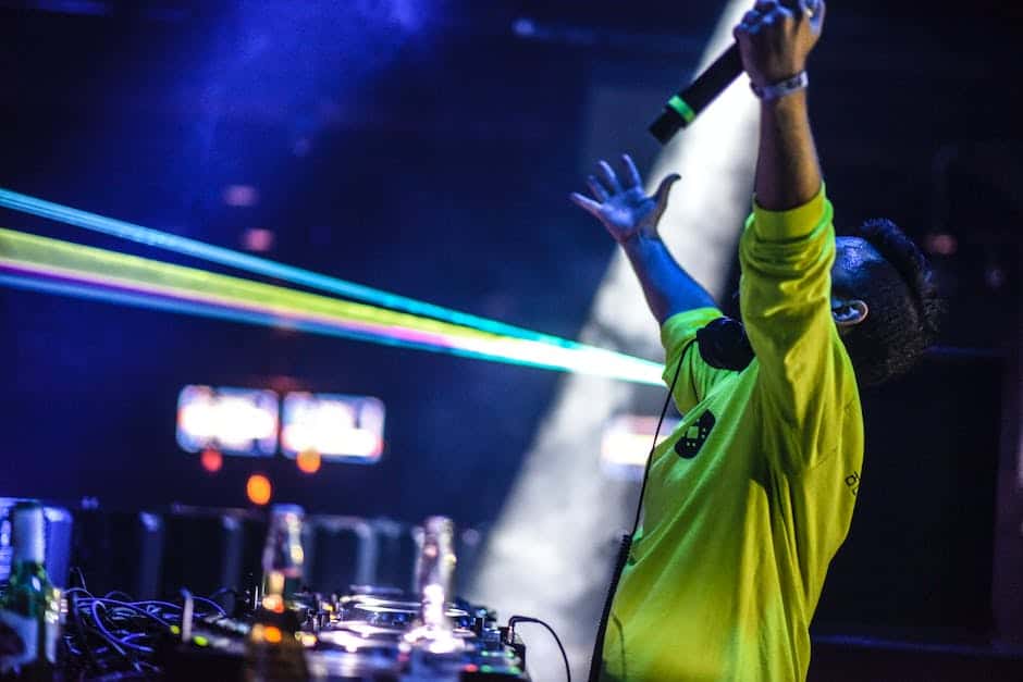 A dj with his hands up in the air at a concert.