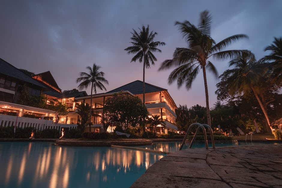 A resort at night with a pool and palm trees.