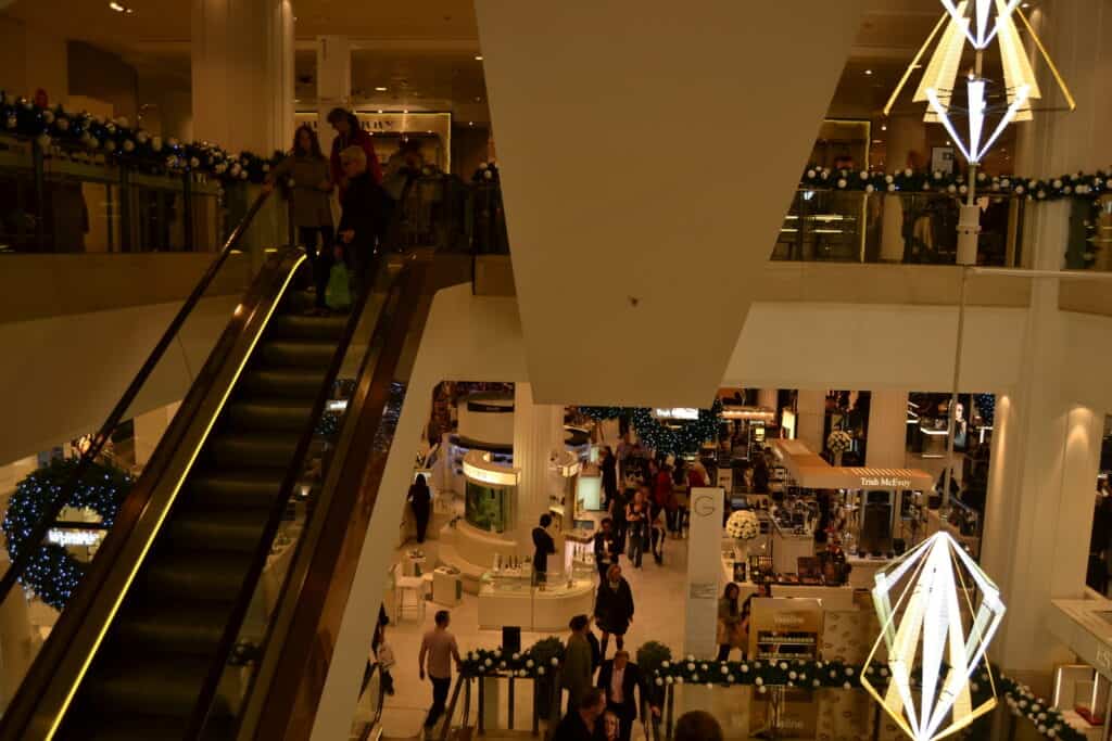 An escalator in a shopping mall with christmas lights.