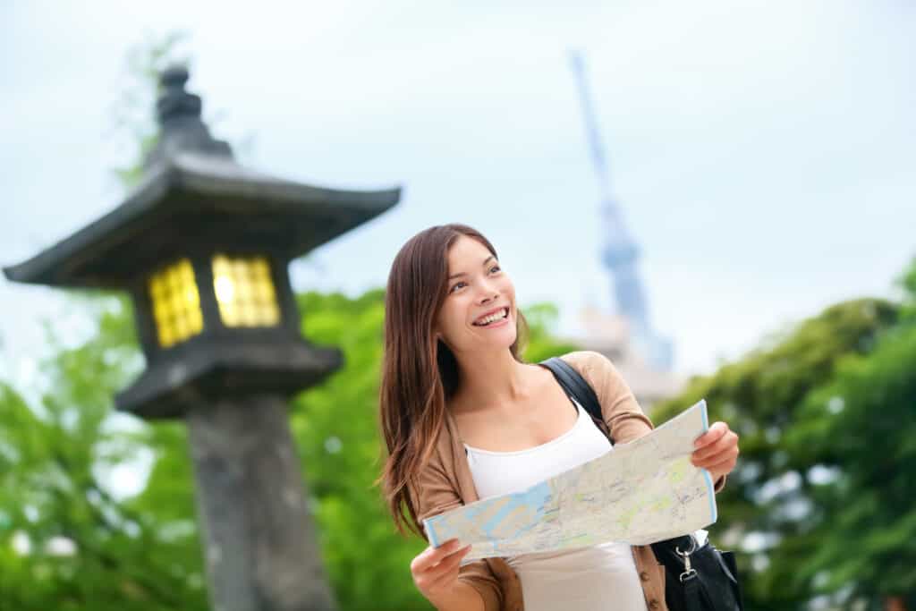 A young woman holding a map in front of a lantern.