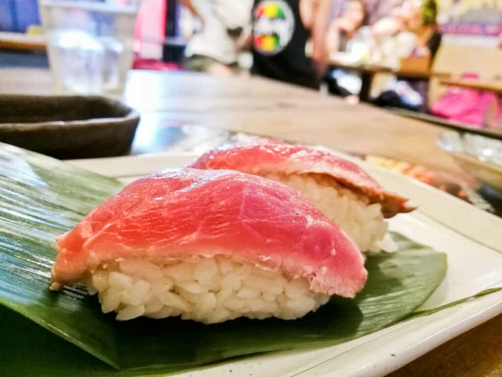 Two pieces of sushi on a green leaf.